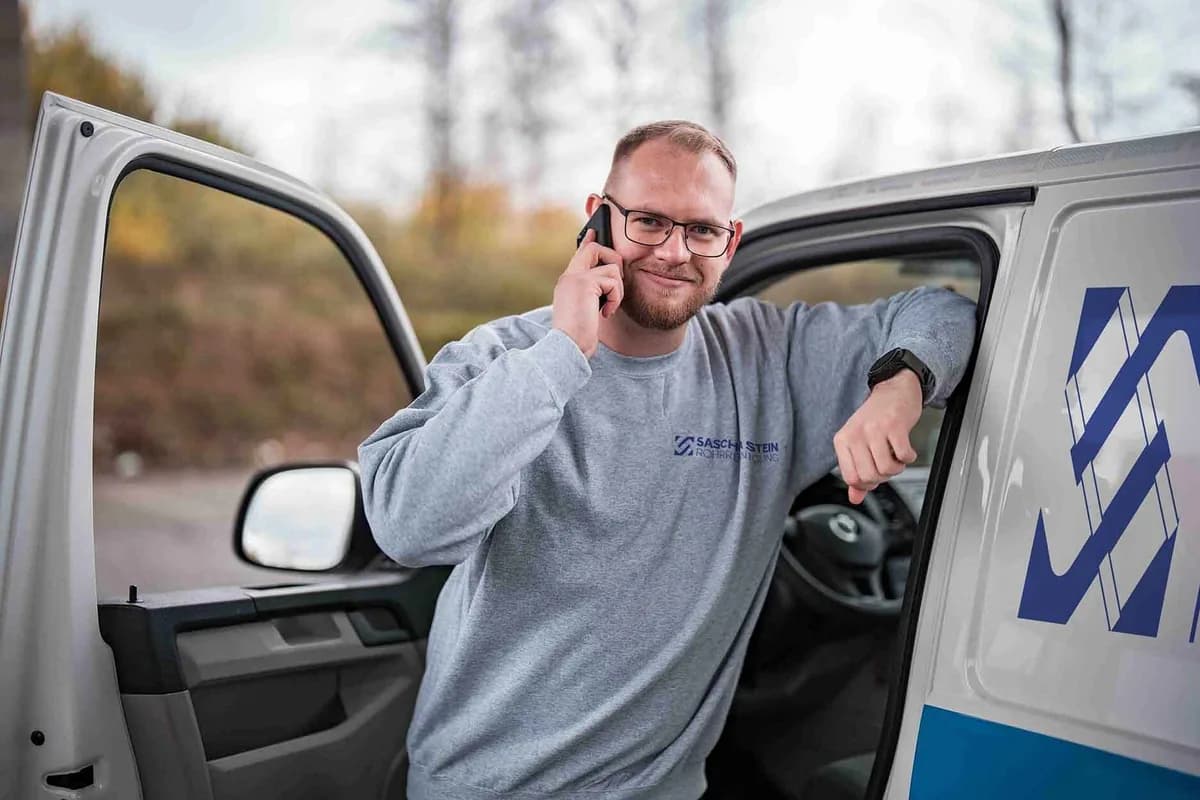 Mitarbeiter der Sascha Stein Rohrreinigung im Kundengespräch am Einsatzfahrzeug